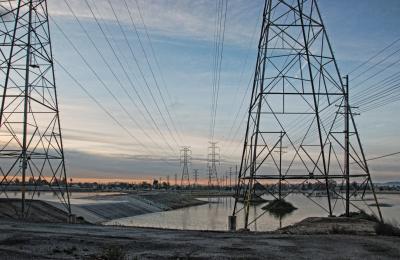 Photograph of power lines above water, with a blue sky in the background.