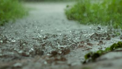 Close photograph of rain falling onto wet ground
