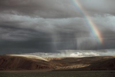 Clouds and a rainbow over a desert-like landscape
