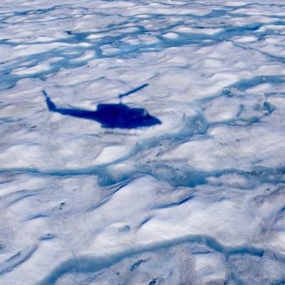 A helicopter flies over the melting Greenland ice sheet. 